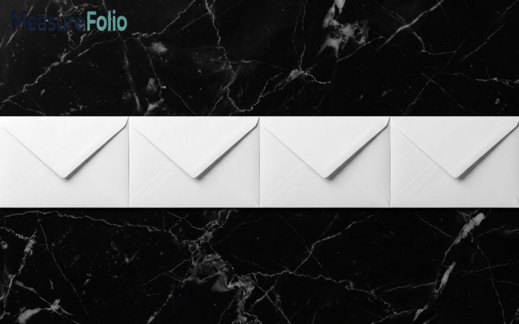 Four white envelopes arranged in a horizontal row on a black marble surface.