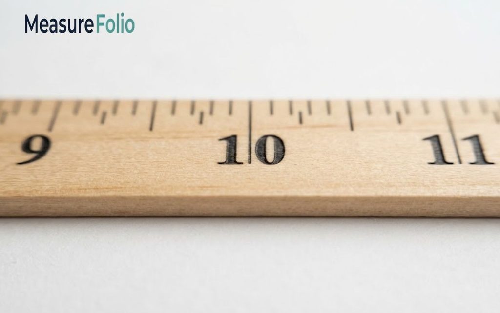 A close-up photograph of a wooden ruler lying flat on a white surface.
The frame focuses tightly on the numbers 9, 10, and 11, highlighting the ten-inch mark.